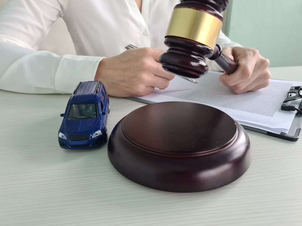 A flipped car and a judge holding a gavel in a courtroom setting.