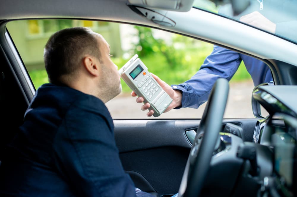 Driver undergoing an alcohol content test using a breathalyzer.






