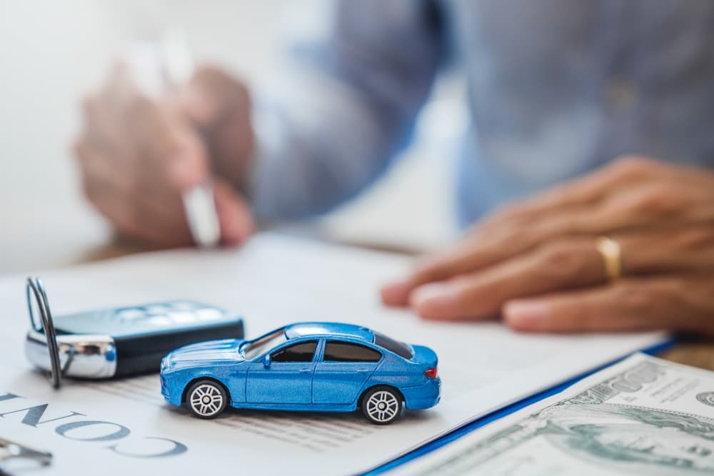 Sales agent finalizes and signs a car loan agreement and insurance contract with a customer.