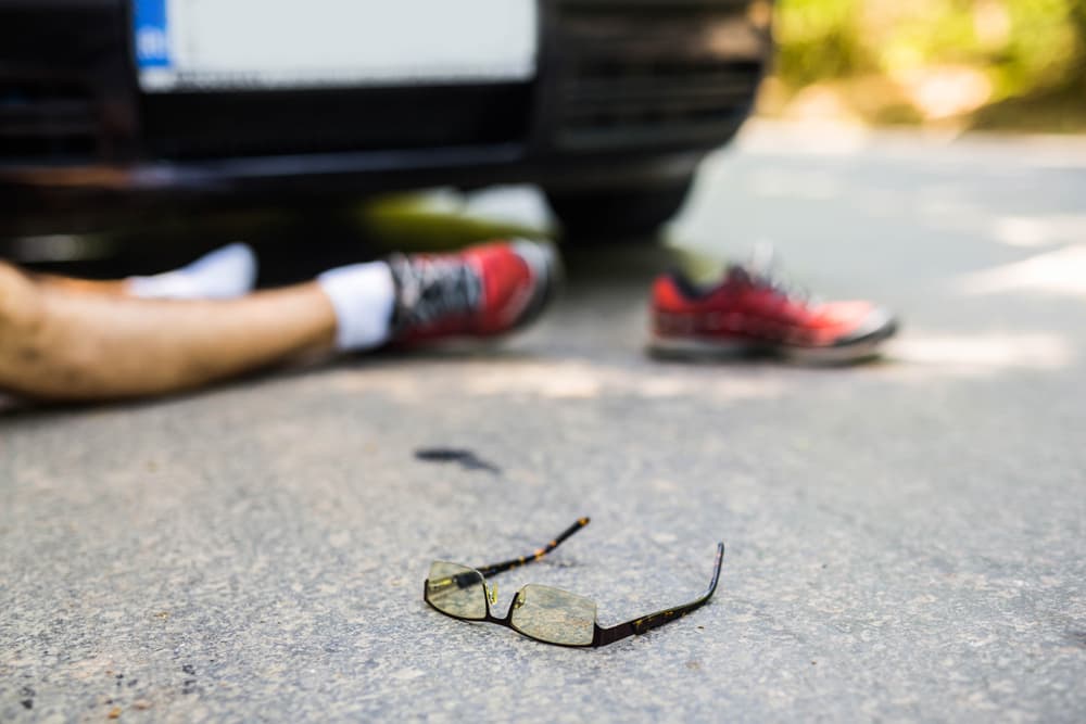 Blurry image of a driver who has hit an unconscious pedestrian; focus on the driver’s eyeglasses.