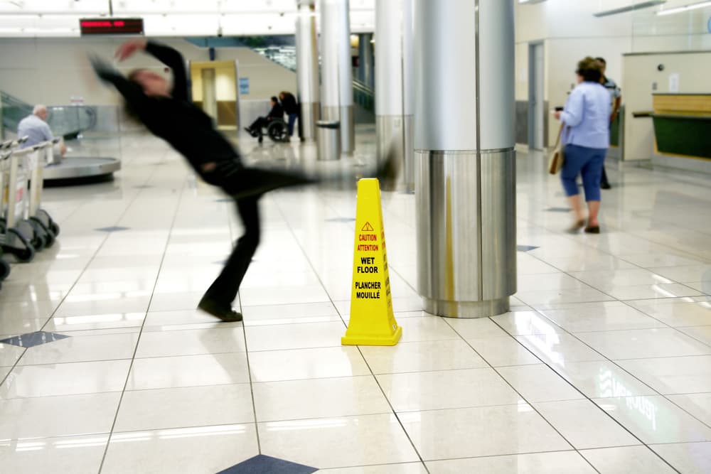 Man slipping next to a Wet Floor sign.






