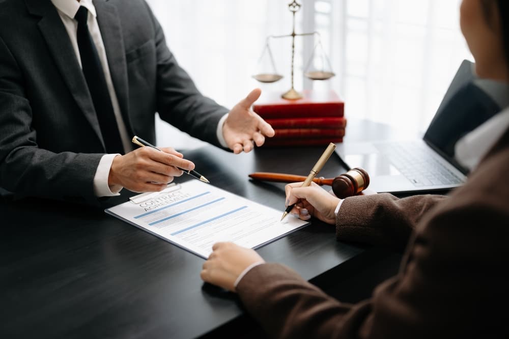 Business and male lawyer or judge consulting during a team meeting with a client. Law and legal services concept emphasizing good customer service and cooperation.