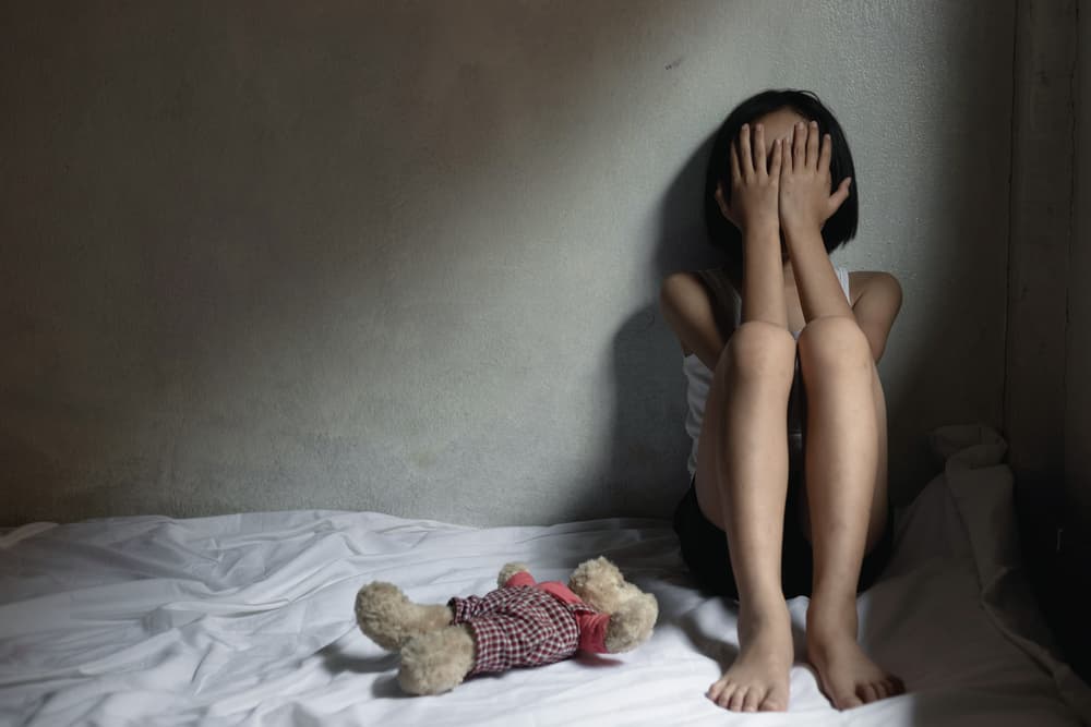 Stop violence and child abuse. A sad little girl sits alone in a room, highlighting the urgent issue of human trafficking.