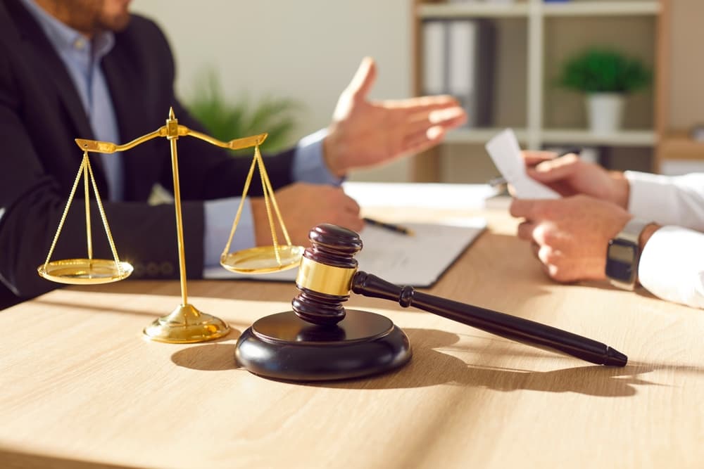 A close-up photo of a male lawyer working at his office desk, engaged in a discussion with a male client. 