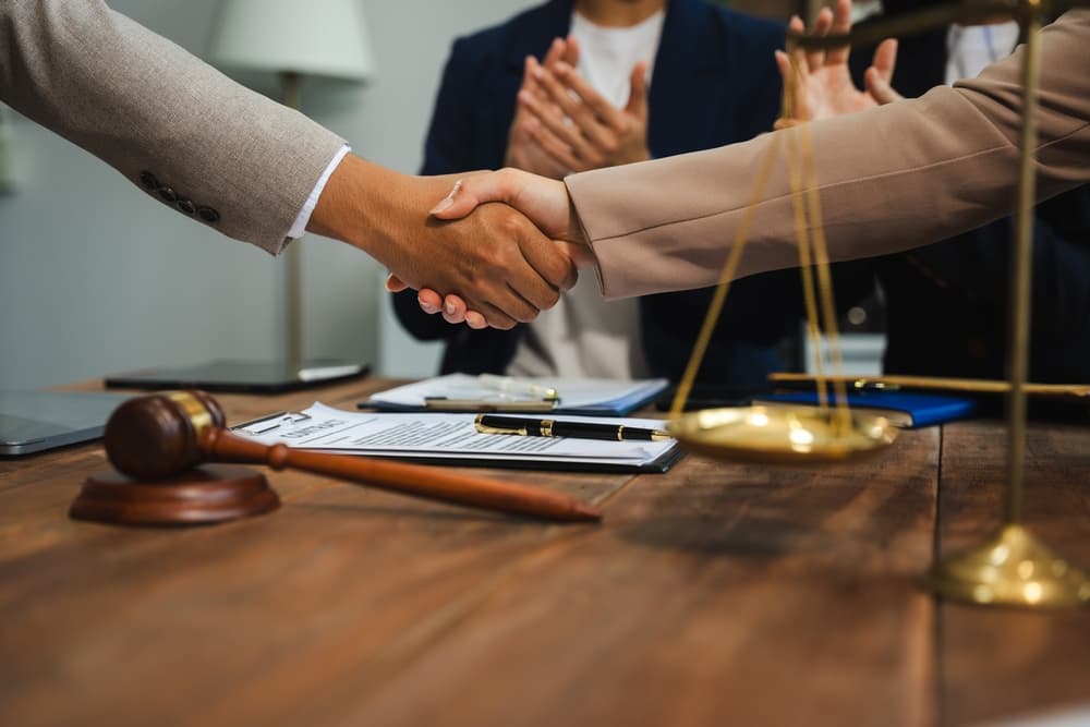 Middle age partner lawyers attorneys shaking hands after discussing a contract agreement done.