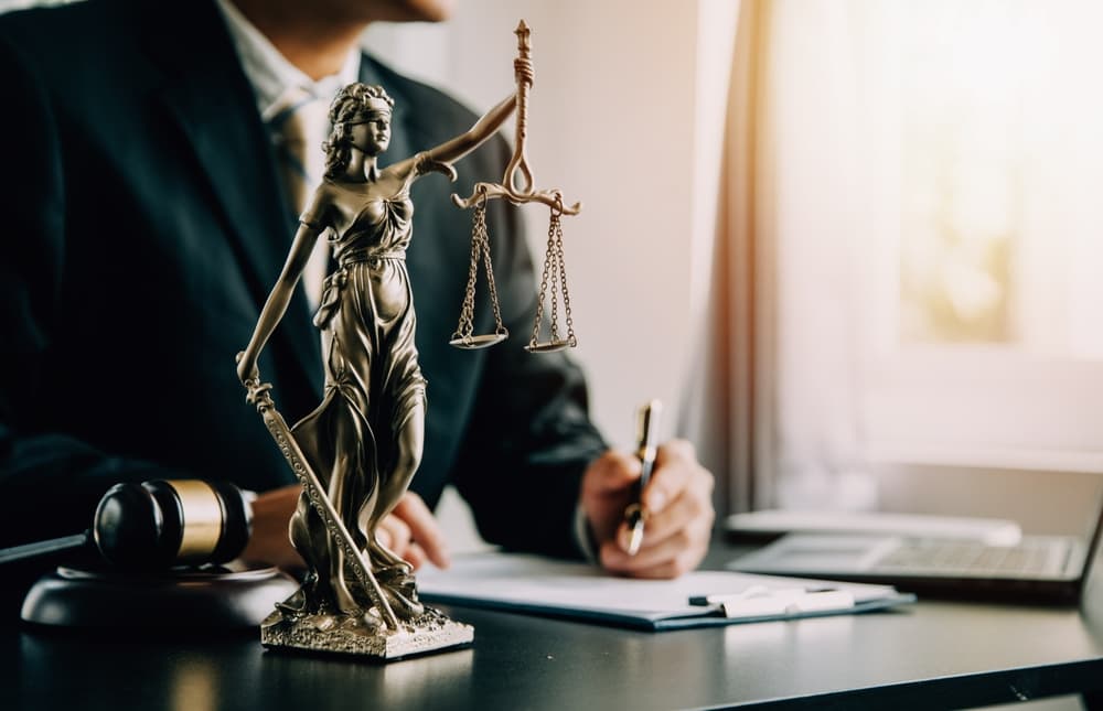 Judge's gavel with justice scales as lawyers hold a team meeting in the background, representing law and legal services.