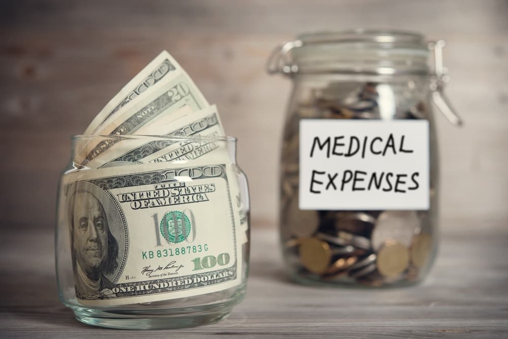 Dollars and coins in glass jar with medical expenses label, financial concept. 