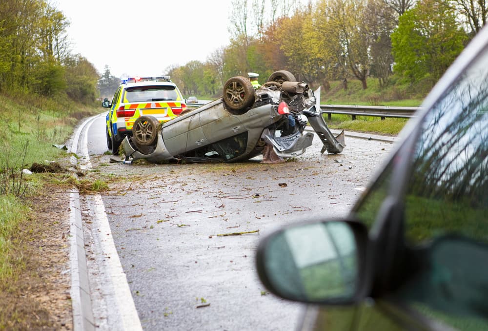 Car lying upside down after a crash on a motorway with a police car beside it