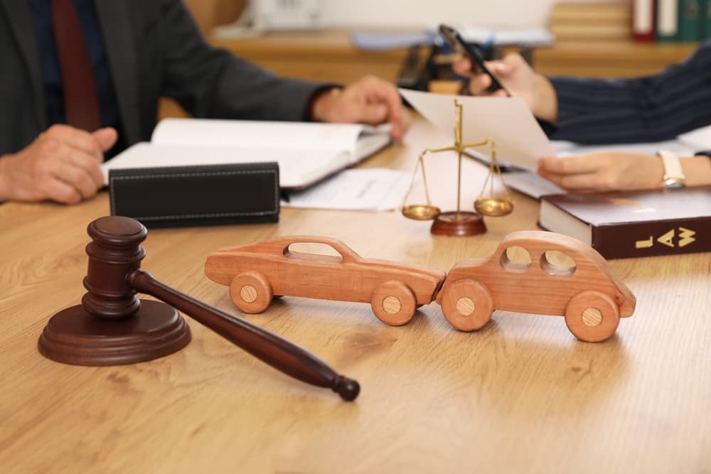 Wooden cars with judge's gavel on car accident lawyer's table during meeting in office