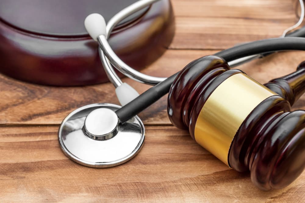 Gavel with stethoscope on wooden table.