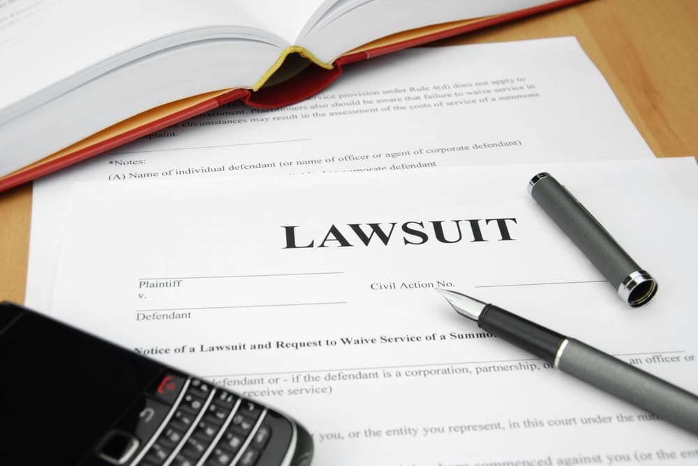 lawsuit form on desk with pen and phone